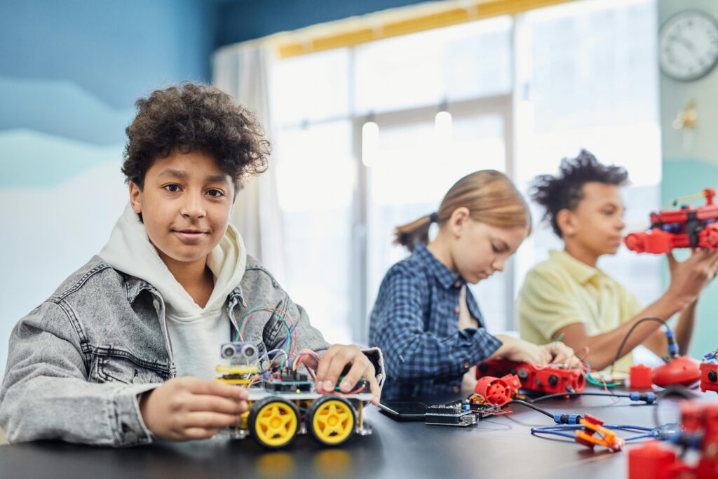 Children learning robotics teamwork with electronic toy projects indoors.